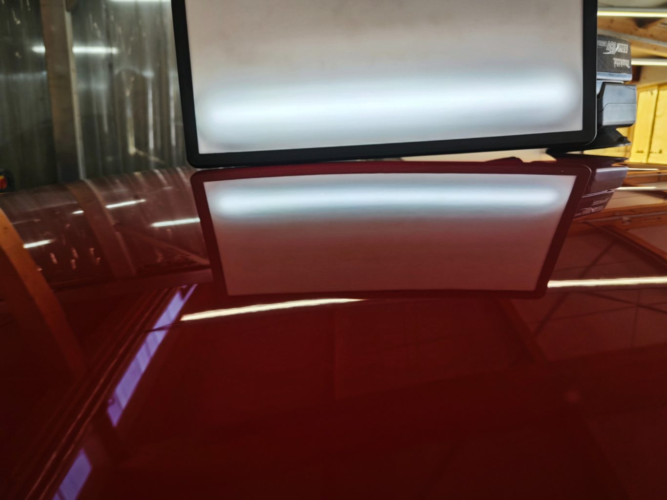 Opel Mokka Dach nachher Rotlackierung mit reflektierender Oberfläche und einem Bildschirm im Hintergrund.