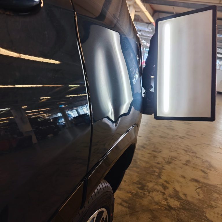 Schwarzes Fahrzeug mit seitlichem Spiegel und reflektierender Oberfläche.