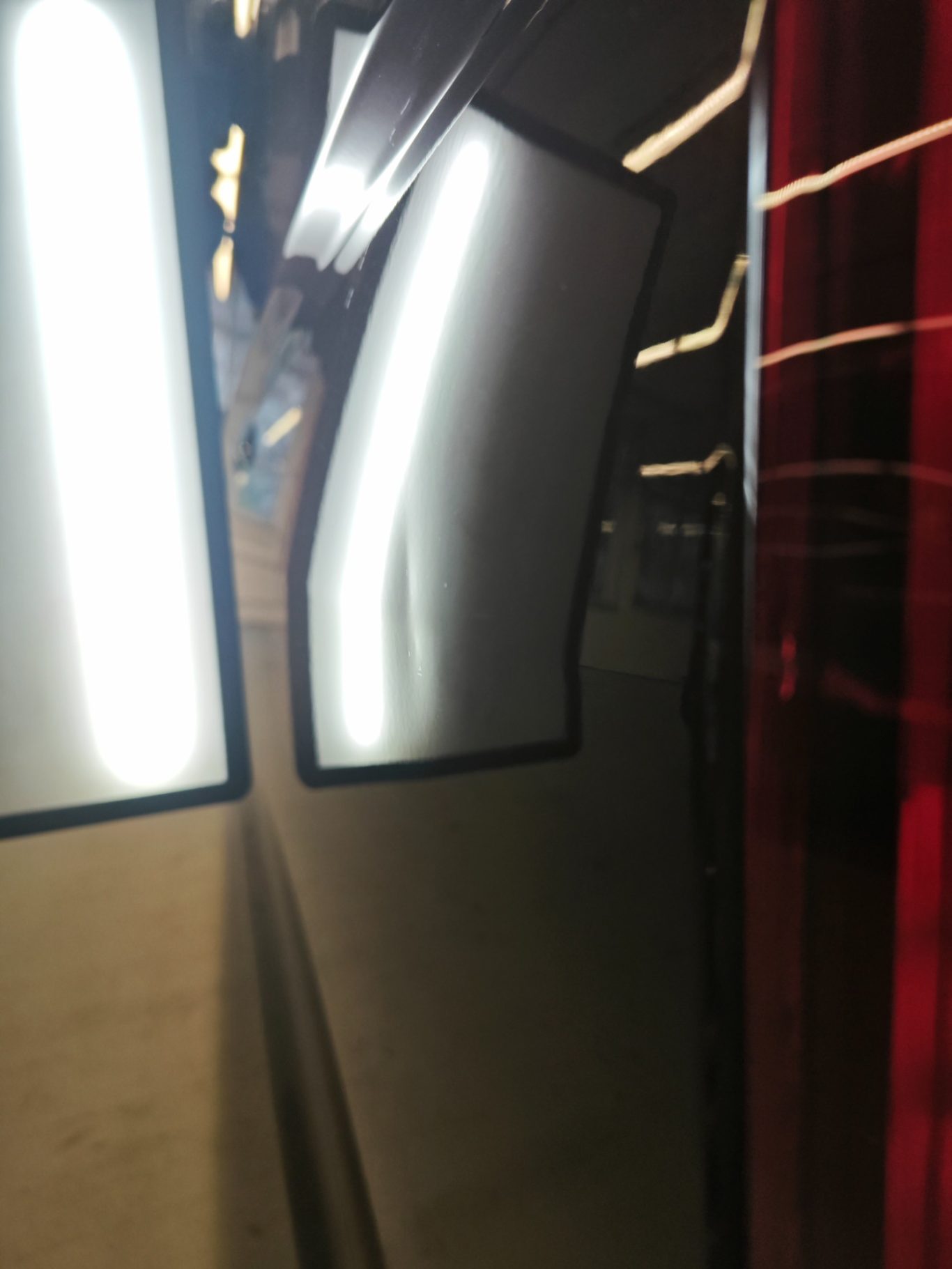 VW T6 Seitenwand vorher Reflektierende Oberflächen in einem dunklen Raum mit hellen Lichtstreifen.