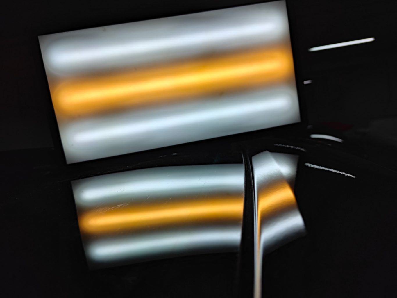 VW Passat Heckklappe nachher Reflektierende Oberflächen mit orangefarbenen und weißen Lichtstreifen.