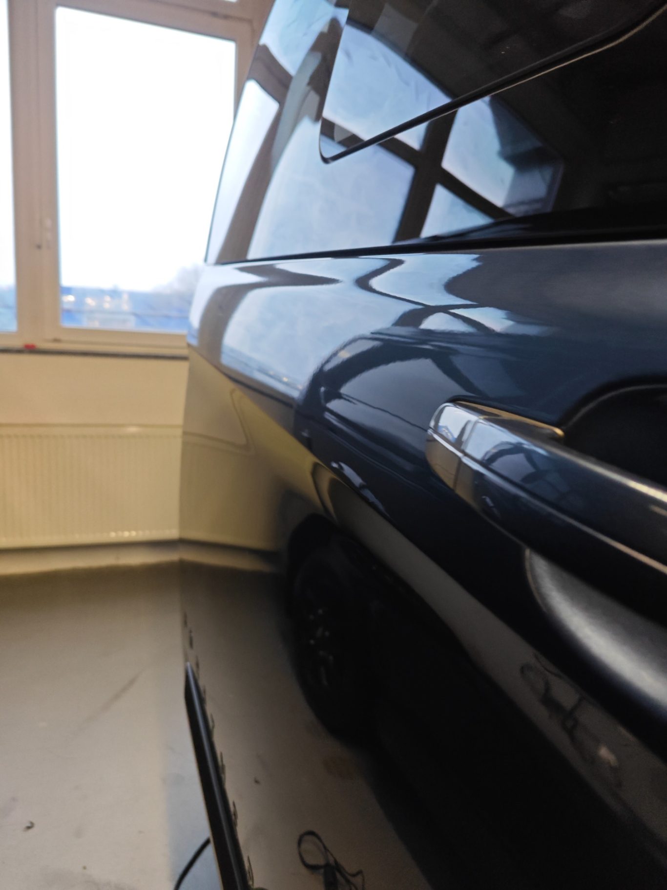 Ford Transit Schiebetüre nachher Schwarzes Fahrzeug mit teilweisem Fensterblick in einem Innenraum.