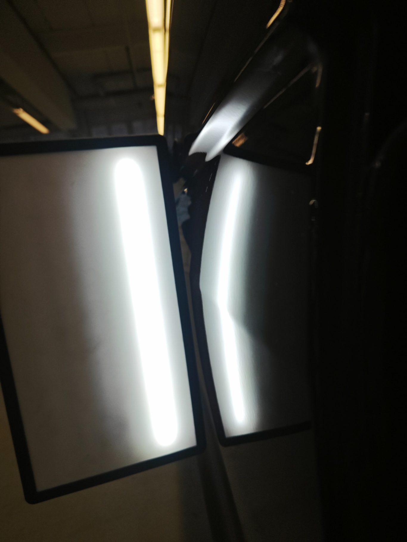 VW T6 Seitenwand nachher Reflektierende Oberflächen in einem dunklen Raum mit hellen Lichtstreifen.