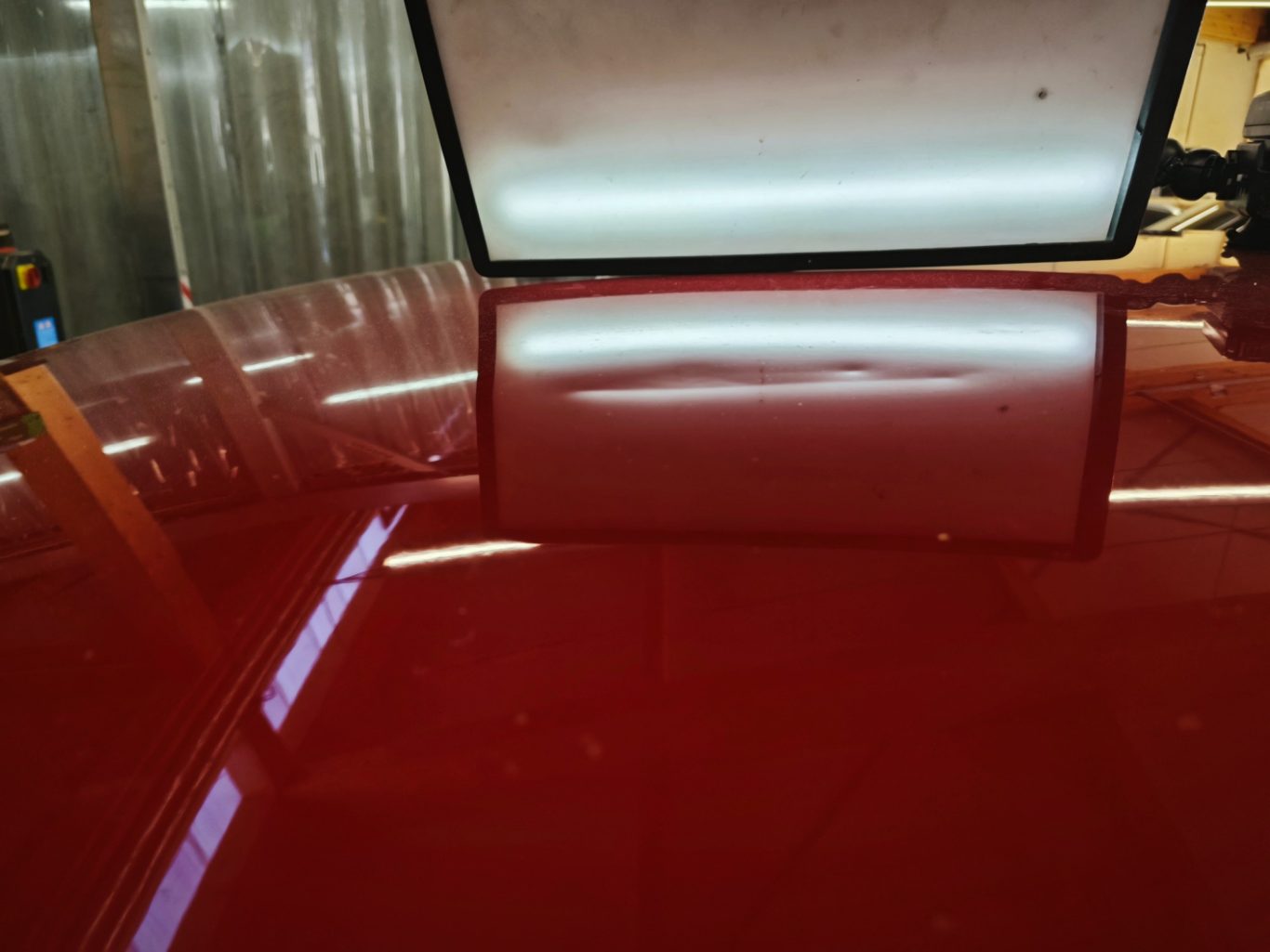 Opel Mokka Dach vorher Rote Autofläche mit reflektierenden Lichtern und einer glatten Oberfläche.