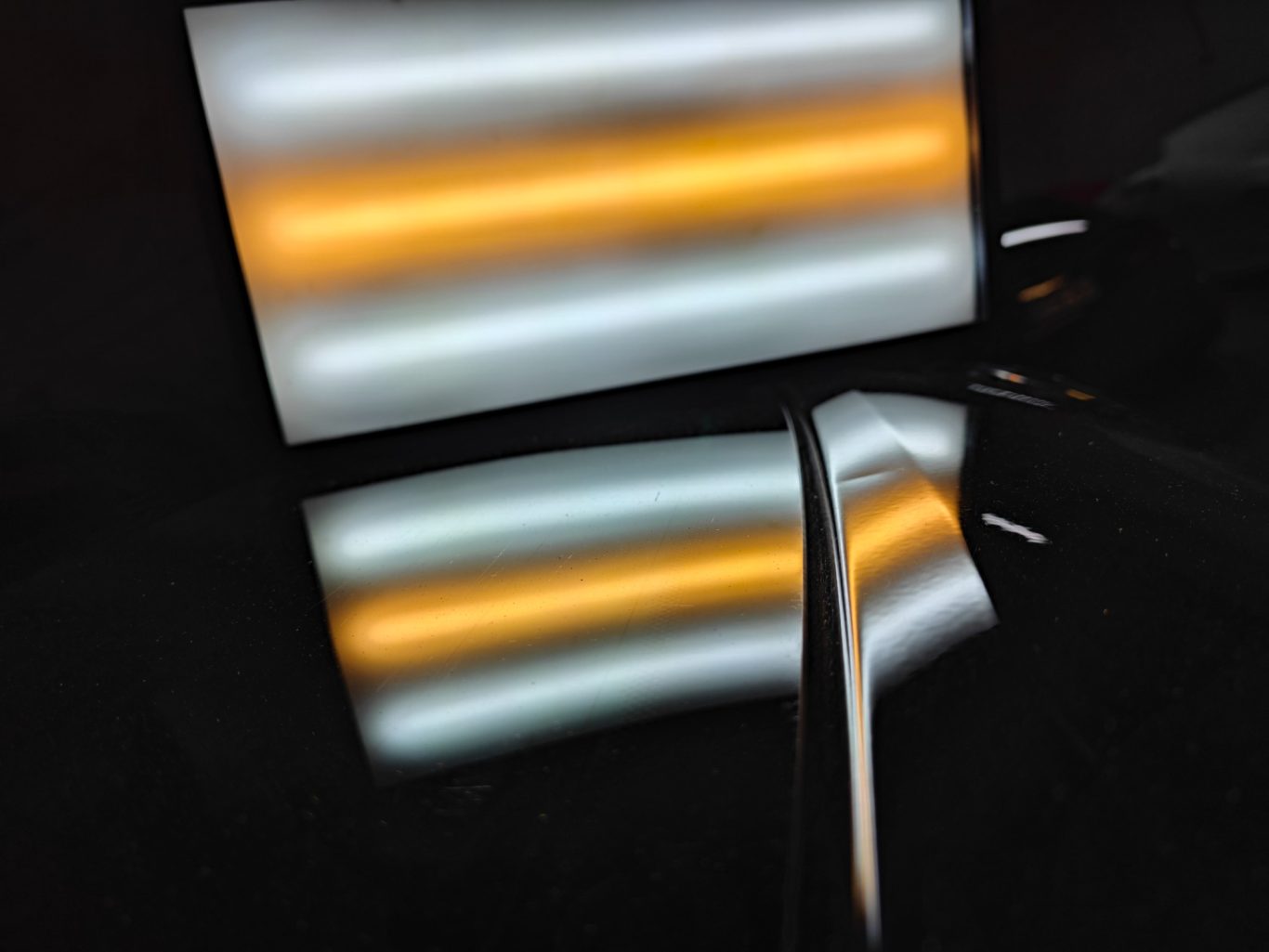 VW Passat Heckklappe vorher Reflektierende Oberflächen mit orangefarbenen und weißen Lichtstreifen.