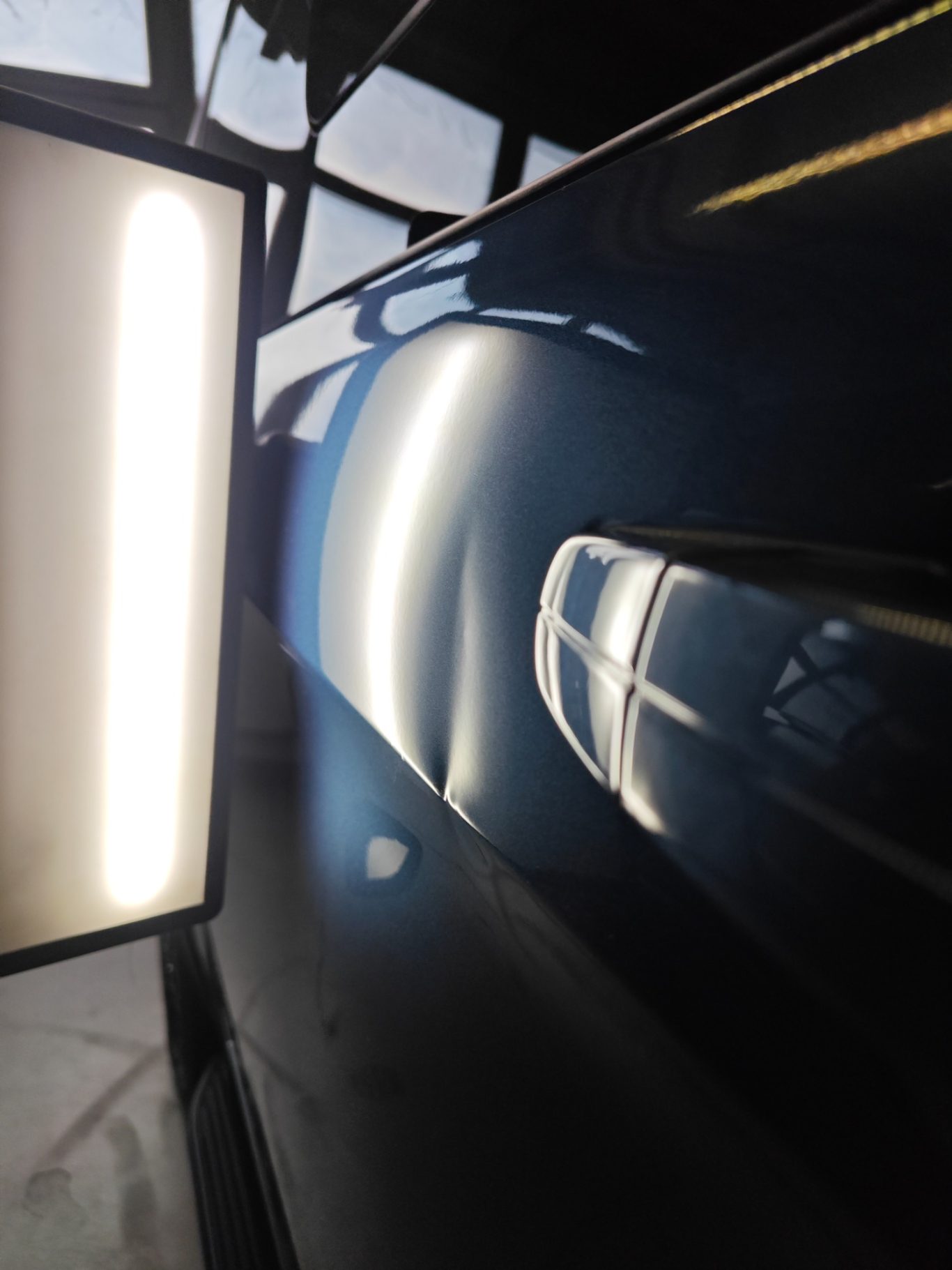 Ford Transit Schiebetüre vorher Reflexion eines Lichtstrahls auf einer glänzenden blauen Oberfläche.