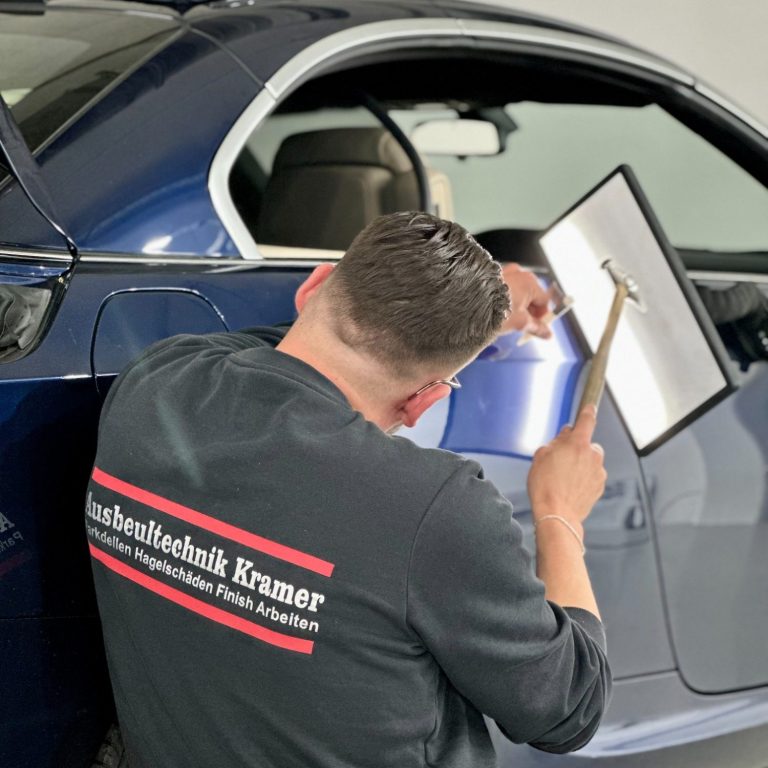 Ein Mechaniker repariert die Karosserie eines Autos mit einem Werkzeug.