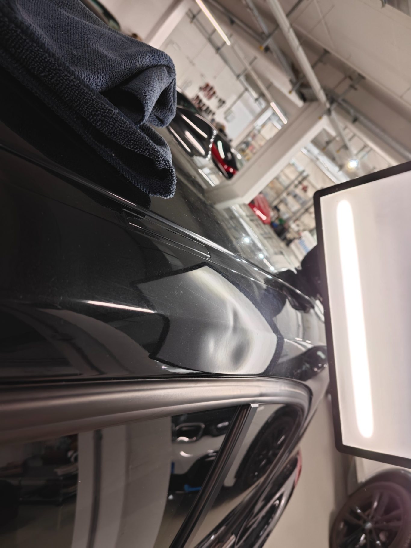 BMW 1er Dachholm vorher Ein schwarzes Auto, teilweise in einer Werkstatt, mit einem Monitor im Vordergrund.