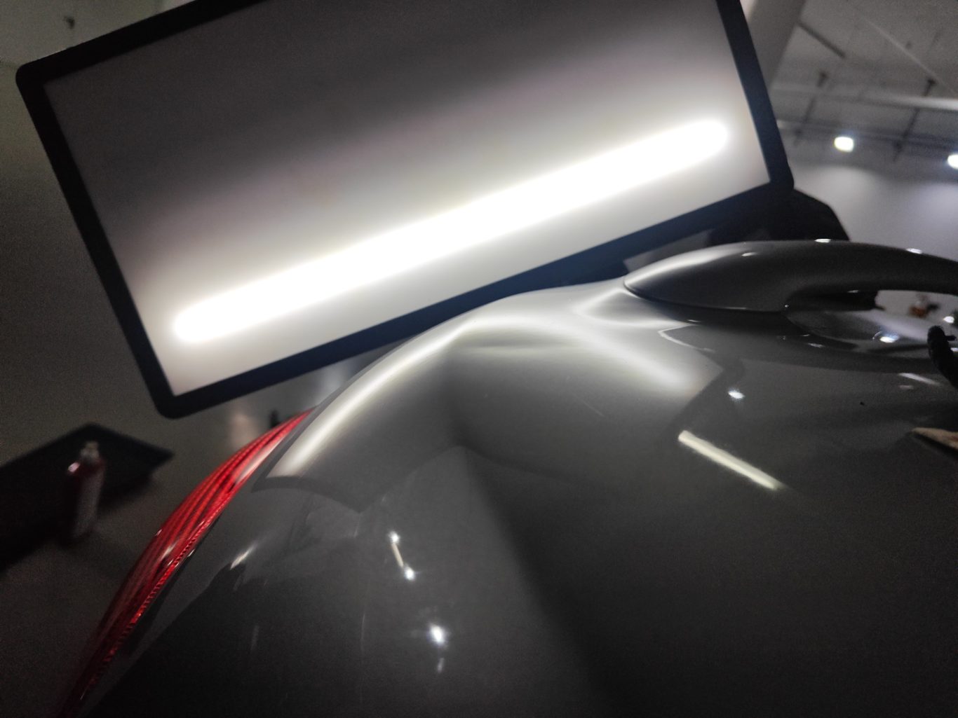 Peugeot 206 CC Heckklappe vorher Graue Oberfläche eines Fahrzeugmodells mit reflektierendem Licht im Hintergrund.