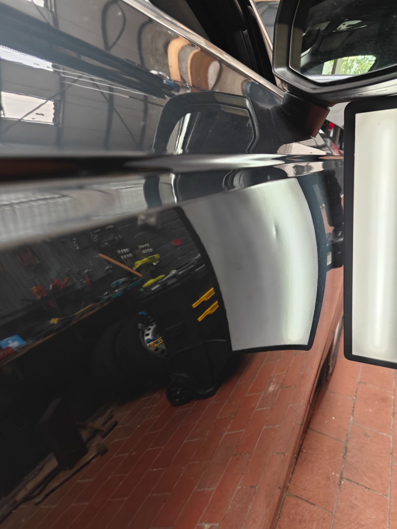 Audi A4 Türe vorher Reflexion auf einer schwarzen Autoscheinwerferverkleidung, Handwerker im Hintergrund.