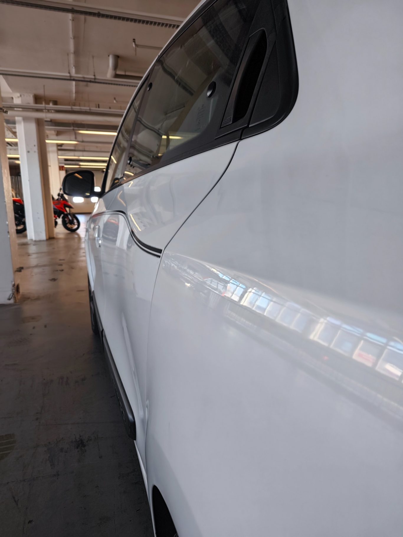 Seitenwand nachher Ein weißes Auto in einer Tiefgarage, seitliche Ansicht mit Betonboden.